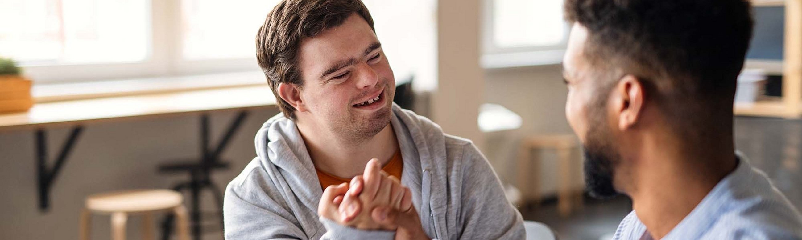 Zwei Männer machen einen Bro-Handschlag, einer hat Down Syndrom